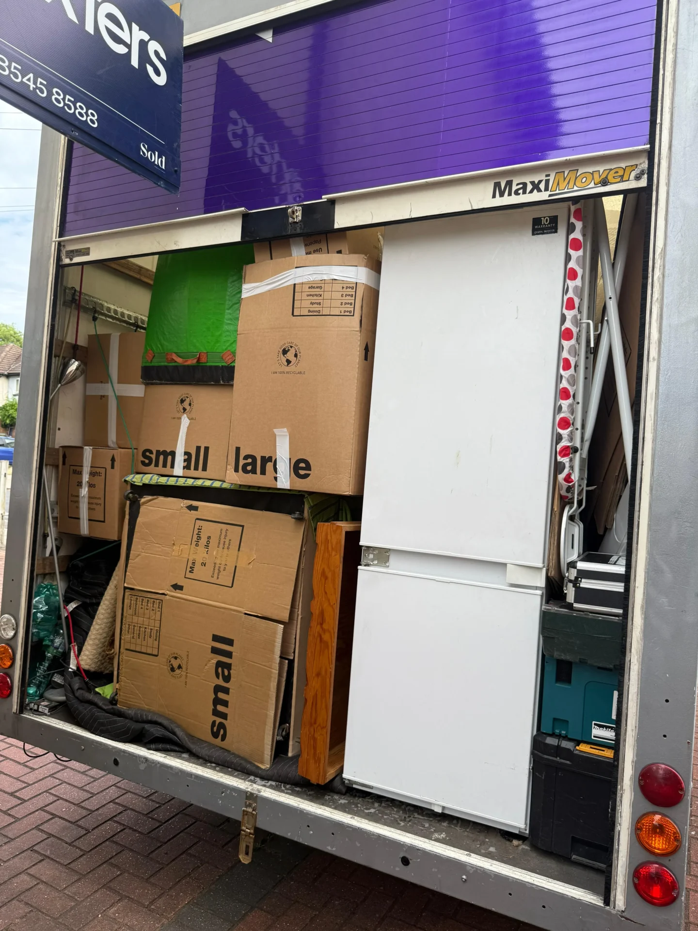 Fully loaded Rad Removals van with labelled moving boxes and furniture, parked outside a London house with a visible Dexters estate agent sign